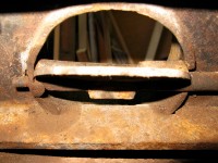 The old rusty integrated flue damper of the cast iron stove