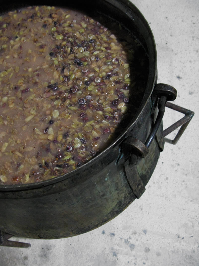 Mass of ripe roditis grapes passed through crusher/destemmers and/or... human feet left to settle for a few days for fermentation to start are placed in the pot at the base of the still in Zagori, Greece